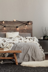 White fury blanket on grey bedding of king size bed with wooden headboard and lights