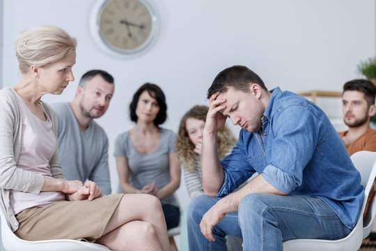 Man with mental disorder during group psychotherapy with therapist