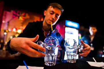 Portrait of a barman or a bartender making an alcohol cocktail in the night club.