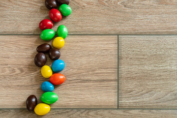 Coated chocolate is arrayed on wooden floor.