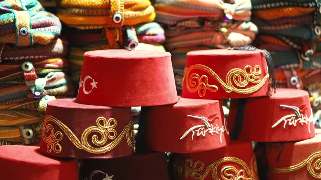 The headdress of the Turkish red Fes is sold on the counter of the market in Turkey. Traditional clothes. Souvenirs and gifts from a tourist trip. Eastern culture