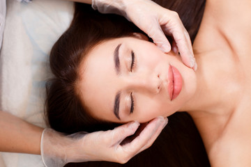 Fototapeta na wymiar Beautiful brunette on facial massage in beauty salon. Top view