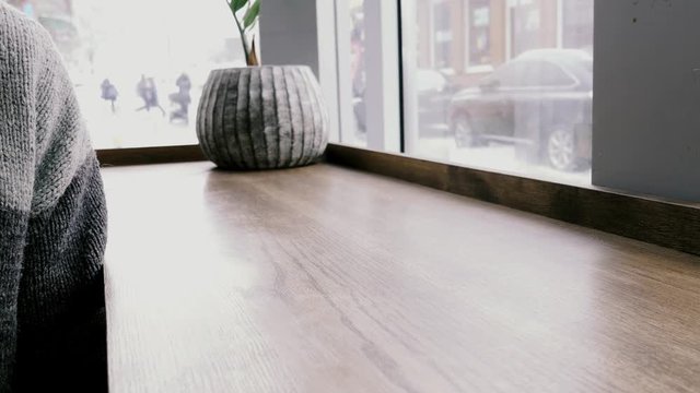 Man in sweater take cup of coffee to drink and pt back on wooden table