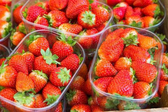 Ripe strawberries in plastic trays on the store counter