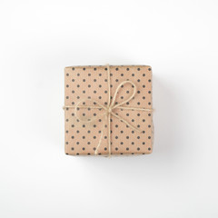  Gift box with brown kraft paper and tied with twine and bow. Isolated on white background, top view, close-up.