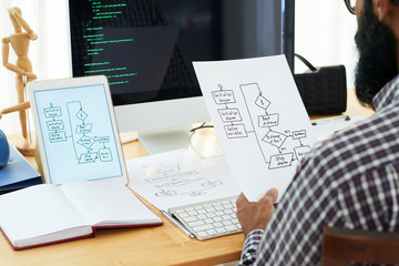 Contemporary it developer looking through papers with sketches of schemes while learning data decoding points