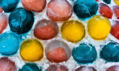 Vividly colored ice balls in snow as a street decoration during winter holidays.