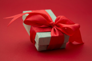 Close up gift box, birtday gift with red bow on red background. Free space for your text. Love, Valentine's Day, Mother's Day.