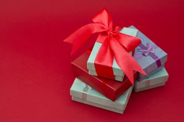 Many colorful gift boxes on red background. Valentine's day, mother's Day, birthday or party concept. Hearts decorations. Copy space.