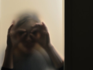 Girl looking behind frosted glass