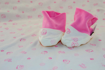 Cute baby stuff! Small stockings for newborn babies, white with pink details on a background with the same pattern.