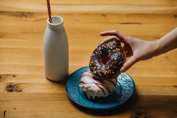 Woman having breakfast of doughnuts and milk served on a wooden table