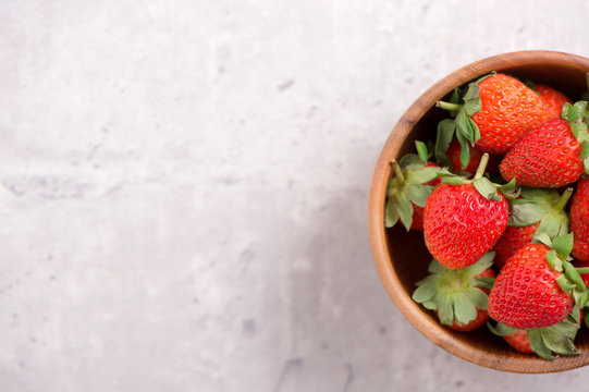 A bowl of beautiful and delicious strawberries isolated on a architectural concrete background, closeup, topview, copyspace.