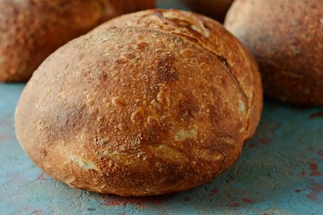 Fresh homemade bread on a gray-blue background, with flax seeds on whole wheat flour. French bread round shape. Bread baking. Unleavened bread
