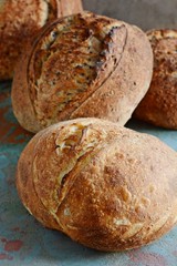 Fresh homemade bread on a gray-blue background, with flax seeds on whole wheat flour. French bread round shape. Bread baking. Unleavened bread