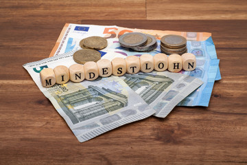 Die Euro Geldscheine und Münzen liegen auf dem Tisch mit dem Wort Mindestlohn