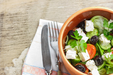 Vegetarian Greek salad with feta cheese, arugula, olives and cherry tomatoes and italian herbs in clay bowl