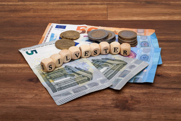 Die Euro Geldscheine und Münzen liegen auf dem Tisch mit dem Wort Silvester