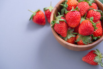 A bowl of beautiful and delicious strawberries isolated on a blue background, closeup, topview, copyspace.