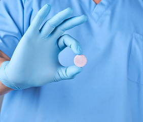 Fototapeta premium doctor in blue latex gloves holding a large round pill