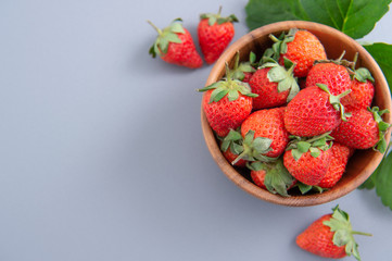 A bowl of beautiful and delicious strawberries isolated on a blue background, closeup, topview, copyspace.