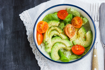 Vegetarian salad with avocado, arugula, cherry tomatoes and herbs.