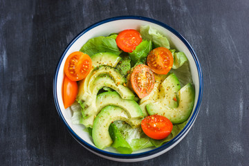 Vegetarian salad with avocado, arugula, cherry tomatoes and herbs.