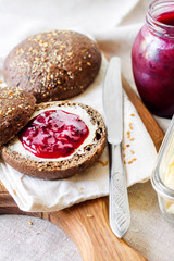 Homemade rye buns with linseeds, sesame and white poppy seeds served with butter and jam