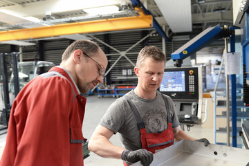 Grupper Arbeiter Teamwork im Stahlbau bei der Konstruktion von Metall an einer Biegemaschine //...