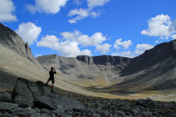 Young white Caucasian male tourist takes photo of beautiful mountains on a sunny summer day