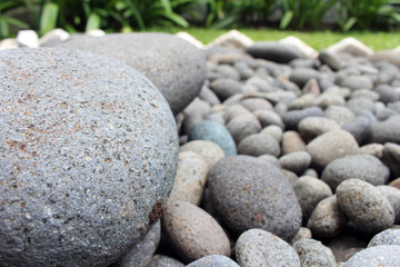 Fototapeta na wymiar Big stones among smaller pebbles, in the garden.