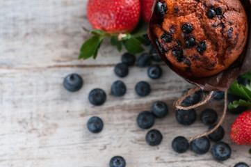 maffin with blueberries and various forest fruits, raspberries, strawberries. There are different types of wood on the table.