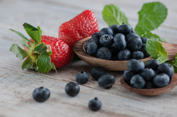 blueberries and various forest fruits, raspberries, strawberries. There are different types of wood on the table.