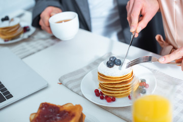 partial view of woman cutting pancakes during breakfast in kitchen