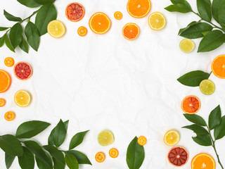 many different fresh citrus fruits on white crumpled paper background