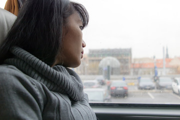 A young woman ride in a bus. Asian girl uses public transport. A bus passenger looking from window.