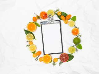 many different fresh citrus fruits on white crumpled paper background