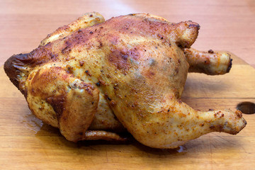 whole roasted chicken in spices on a wooden tray