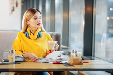 Beautiful blue-eyed woman holding cup with tasty latte