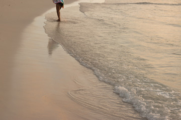 Legs of Woman Standing in Pleasant Soothing Wave of Sea on Sandy Beach at Sunset of Day. Concept: Summer Vacation.