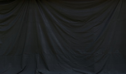 Background image of black canvas curtain hanging with wrinkles