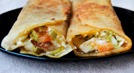 Tortilla. Chicken with vegetables in pita bread. Fried dish on the plate. Close-up
