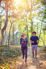 Naklejka na ściany i meble Cardio exercise - couple enjoying in a healthy lifestyle while jogging along a forest,.
