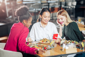 Obraz na płótnie Canvas Businesswomen eating tasty salads and having video chat with friend