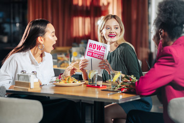Woman showing her best friends book about finding husband