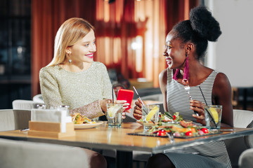 Two stylish cheerful women wearing nice dresses having lunch