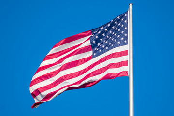 Flag of United States of America waving in wind, against clear sky