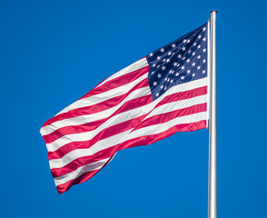 Flag of United States of America waving in wind, against clear sky