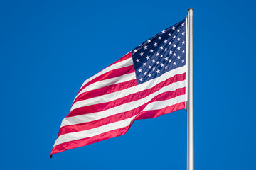 Fototapeta premium Flag of United States of America waving in wind, against clear sky