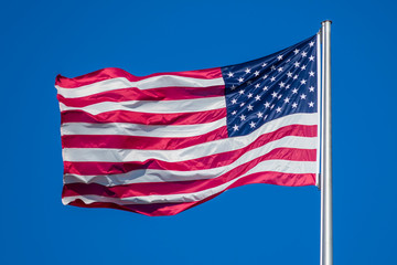 Fototapeta premium Flag of United States of America waving in wind, against clear sky